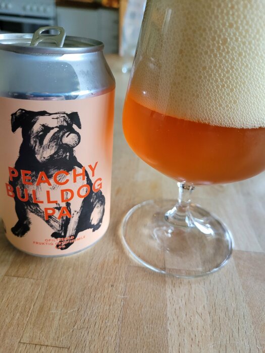 En burk öl med en bulldogg och texten "Peachy Bulldog PA" bredvid ett glas med skummande öl.