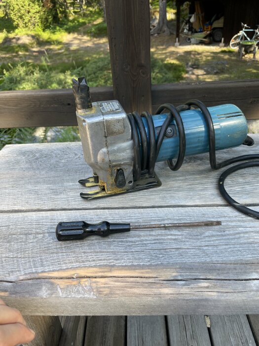 Elektrisk sticksåg och skruvmejslar på träbänk, utomhus, verktyg för snickeri eller hantverk.