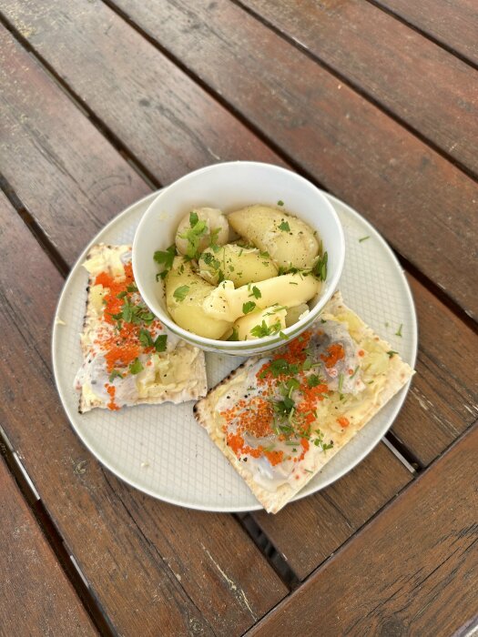 Knäckebröd med pålägg, kokta potatisar, persilja, löjrom, på trädgårdsbord.