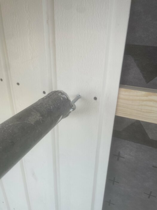 Borr används för att skruva in skruv i en vitmålad träpanelvägg, arbete pågår.