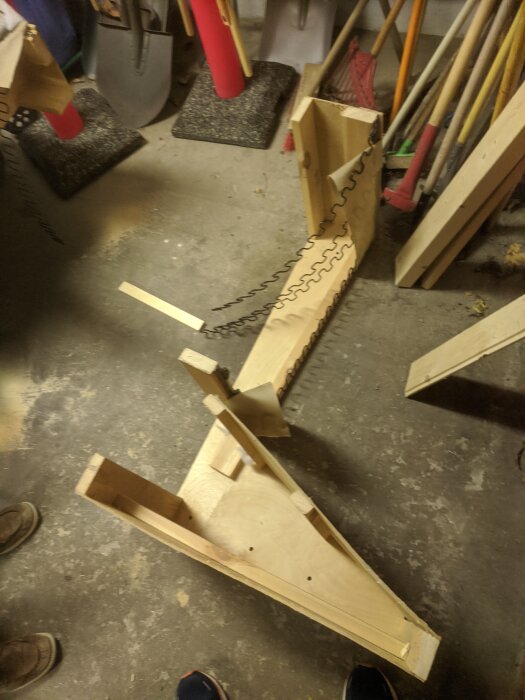 Träkonstruktion på betonggolv. Såg, verktyg, spån, benämnd som kreativt eller improviserat arbete.