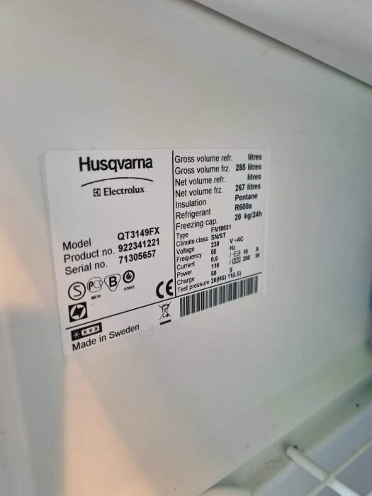 Etikett på Husqvarna/Electrolux kylskåp visar modell, volym, kylmedel, energiklass och tillverkning i Sverige.