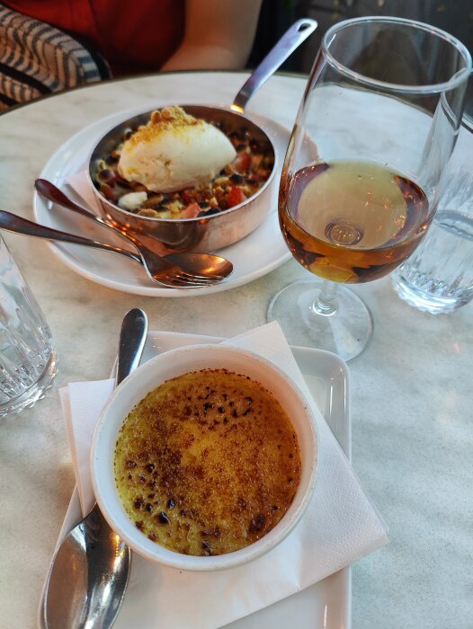 Middag med crème brûlée, ratatouille, glass, och ett glas konjak på ett bord.