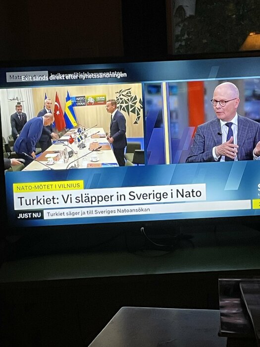 Nyhetsprogram med text "Turkiet: Vi släpper in Sverige i Nato", NATO-möte, personer vid bord, svensk flagga, diskussion.