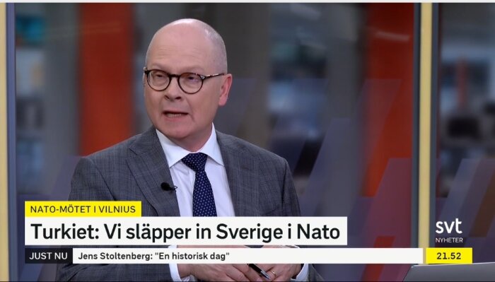 Man i kostym talar på TV, nyhetstext om Sverige och Nato, studio bakgrund.