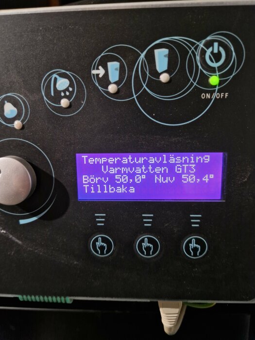 Digital kontrollpanel för temperaturinställning med ikoner, knappar och en belyst skärm på en apparat.