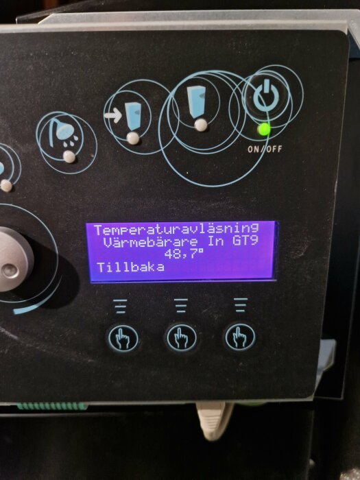Styrenhet med temperaturvisning, knappar och ikoner för dusch eller värmare, påslagen med grön lampa.