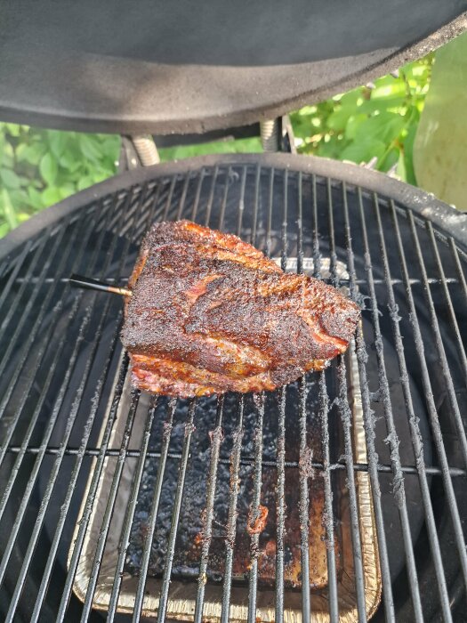 Kryddat kött grillas på kolgrill, vackert brynt yta, matlagning utomhus, somrig atmosfär.