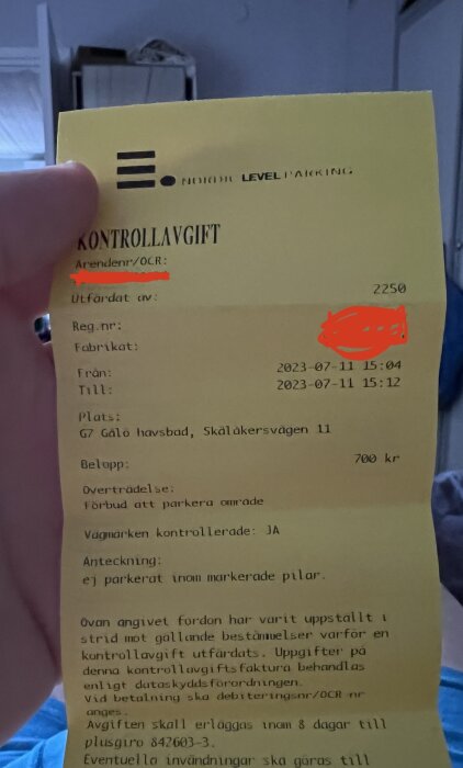 Kontrollavgift (parkeringsböter), utfärdad för felaktig parkering, gul bakgrund, handhållet, personliga uppgifter dolda.