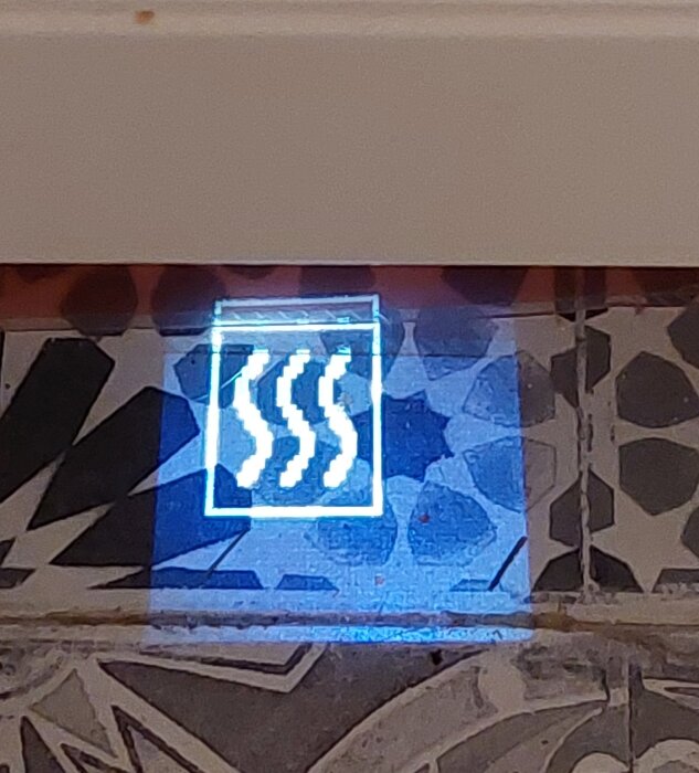 Belyst skylt med tre pilar som pekar diagonalt uppåt, monterad på vägg med mosaikmönster.