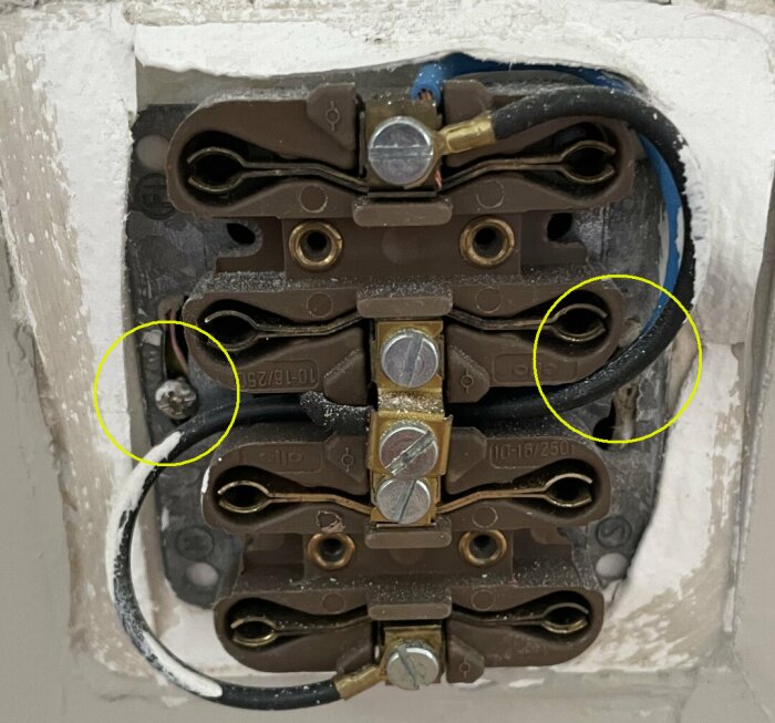 Öppen eluttagskonsol med synliga anslutningar, trådar och skruvar. Gul markering indikerar potentiella problem.
