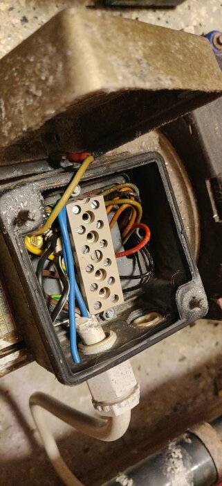 Elutrustning med öppen anslutningslåda och flera ledningar kopplade till en skruvplint, behöver ordentlig rengöring.