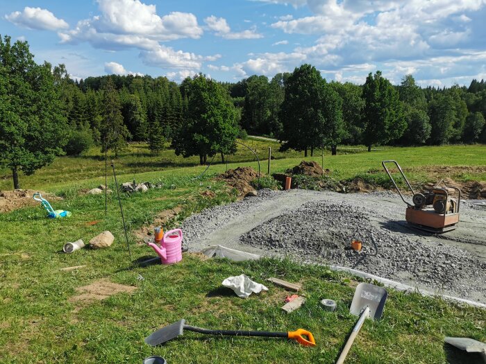 Byggarbetsplats utomhus med markarbeten, verktyg, leksaker och grönt landskap.