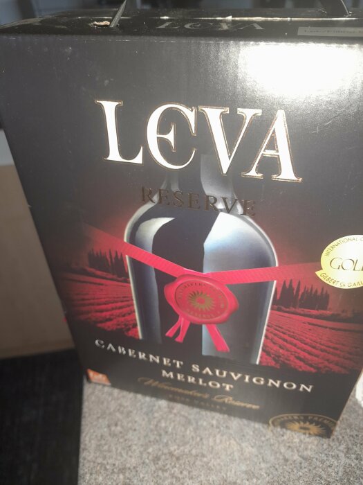 En box med rödvin märkt "LEVA RESERVE Cabernet Sauvignon Merlot", priser och medaljer synliga.