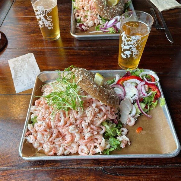 Skaldjursmacka, räkor, bröd, öl, sallad, träbord, måltid för två personer, avslappnad atmosfär.