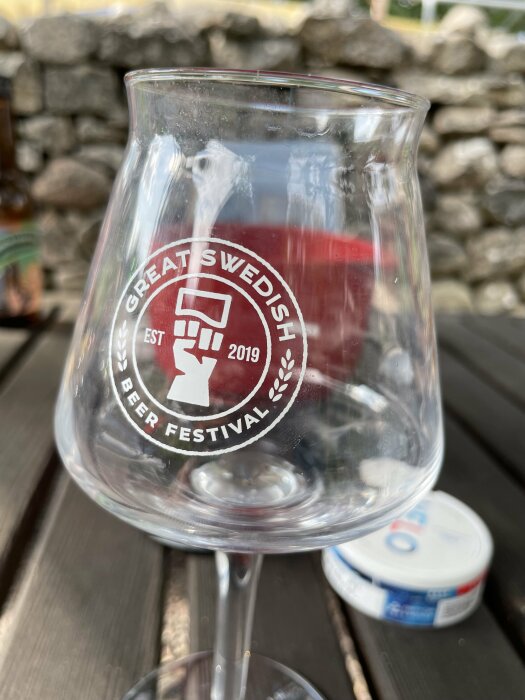 Ett tomt ölglas med logotyp, Great Swedish Beer Festival, utomhus på ett bord.