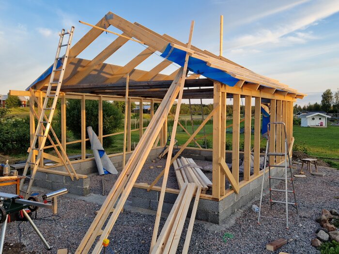 Trästomme till byggnad under konstruktion, stegar, klar himmel, grunda fundament.