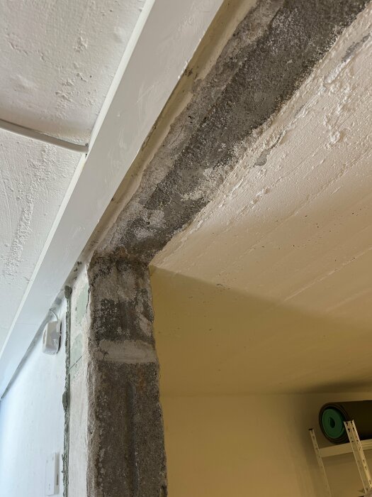 Ett hörn i ett rum med synligt slitage eller vattenskada på vägg och tak.