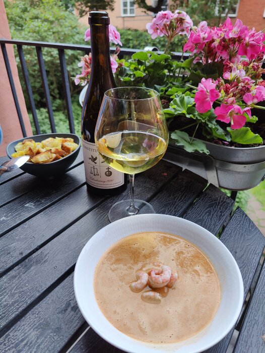 Middag på balkong; skaldjurssoppa, potatisgratäng, vitt vin, blommor, urbana miljön.