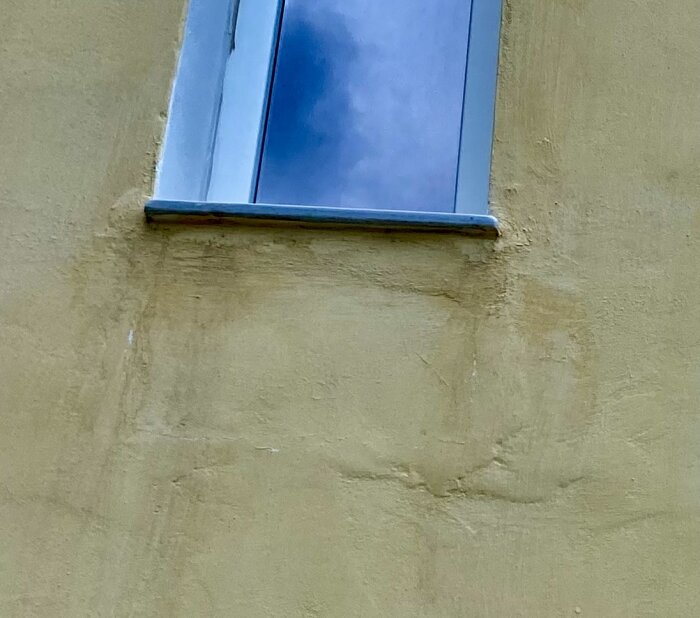 Stängt fönster, gul vägg, reflekterande blå himmel, arkitektonisk detalj, stadsbyggnad.