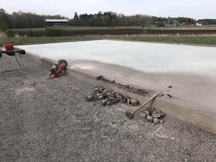 Ny betongplatta, verktyg, kantsten, landsbygd, grus, byggnadsarbete utomhus, avsatt område.