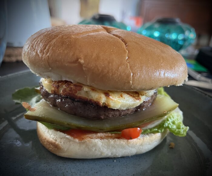 Hamburgare med kött, ost, sallad och sås på ett tallrik. Närbild, diffust bakgrund.