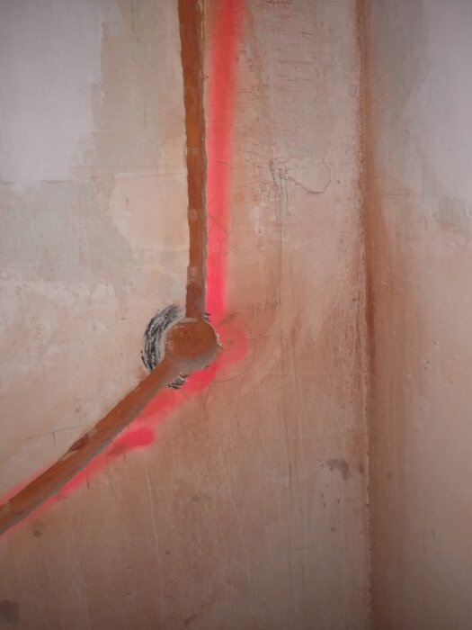 Rödlaserlinje på vägg med skrovlig yta, markerar genomgång, byggnadsinspektion eller installationsarbete.