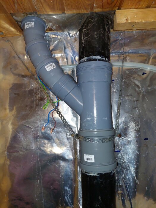 VVS-installation med rör, isolering och elektriska ledningar i innervägg.