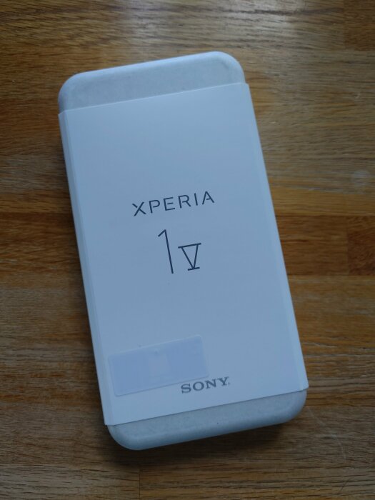 En låda för Sony Xperia 1 IV smartphone ligger på ett träbord.