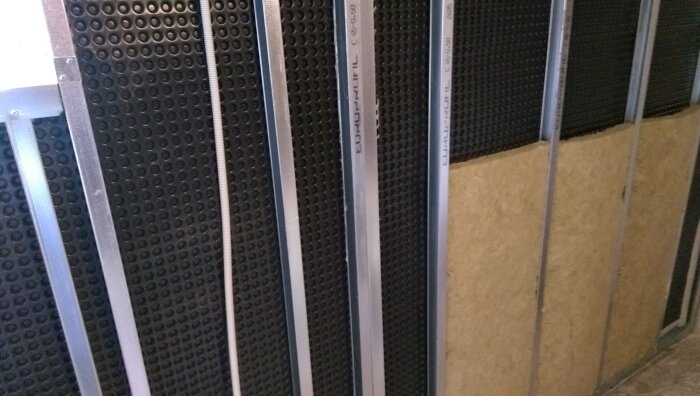 Serverrack med svart perforerad front, kablar, och metallstänger i ett datacenter.