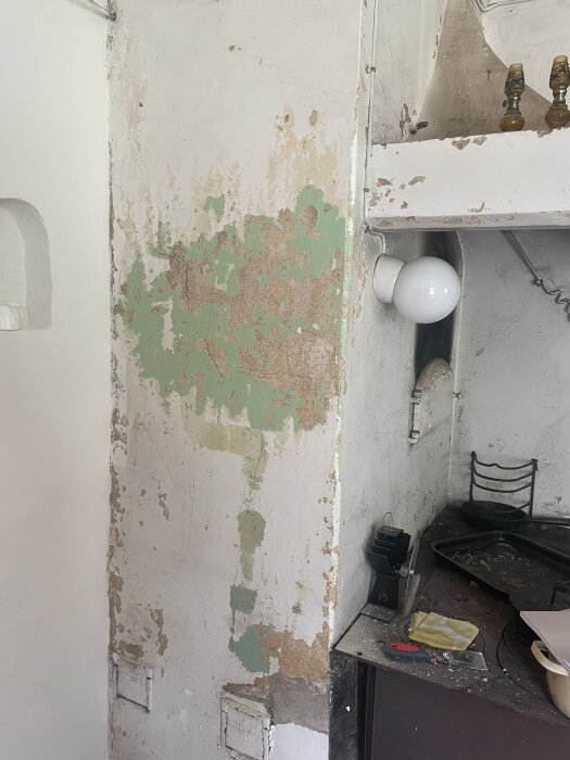 Föråldrat kök, flagnande väggfärg, orenoverat, spis, diskbänk, oorganiserat, behöver underhåll, slitet.