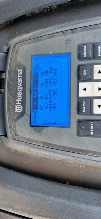 Digital display with numbers on blue background, dusty Husqvarna equipment, buttons for operation.