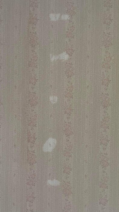 Vertikal tapet med sliten, blommig design och slitagefläckar, i beige, grönt och rosa.