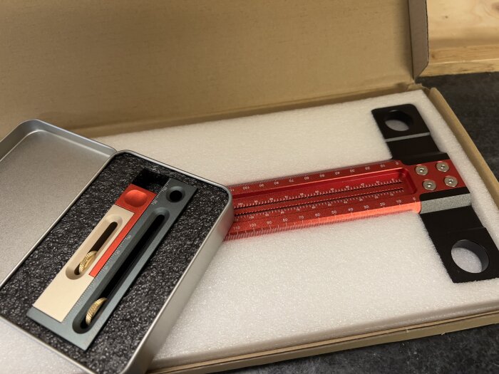 Precisionstillbehör i fodral: vinkelmätare, knivar, röd linjal, packat i skuminsats.