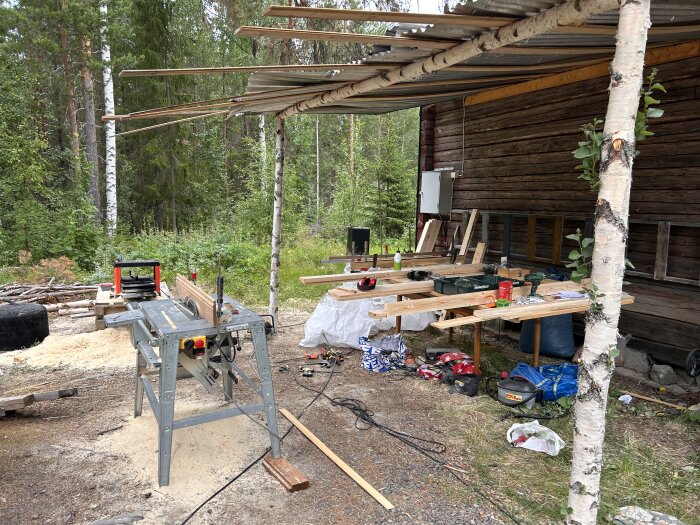 Verktyg och byggmaterial vid träbyggnad i skogen, pågående arbete eller renoveringsprojekt.