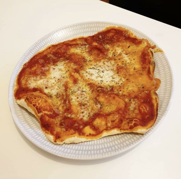 En ostig, gyllenbrun omelett på en vit tallrik, övertäckt med tomatsås och kryddad med svartpeppar.