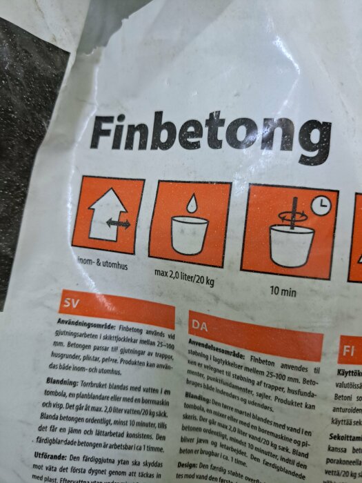 En etikett för "Finbetong" med instruktioner och ikoner, delvis skadad, språk: svenska, danska, finska.