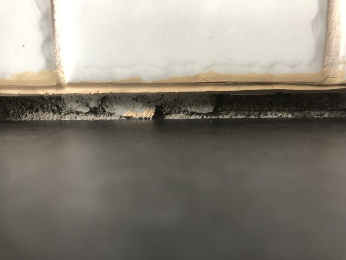 En närbild på en skadad fog mellan vägg och bänkskiva med mögel och fuktspår.