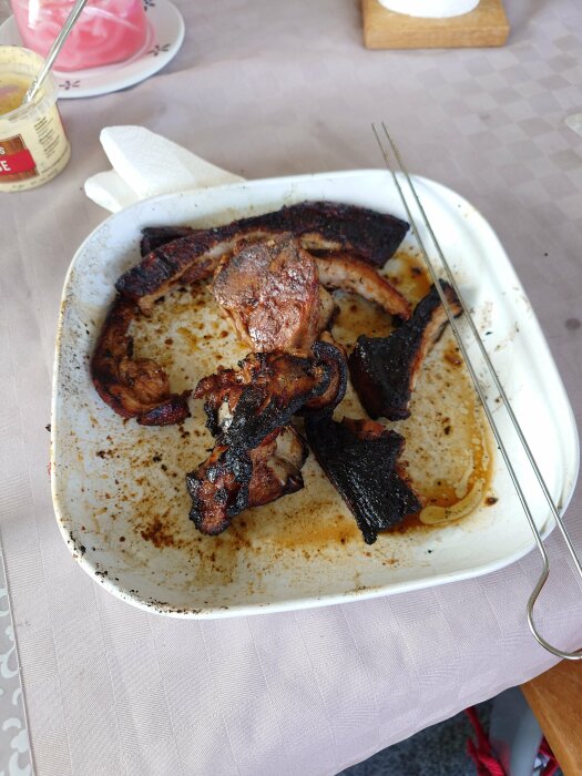 Stekt bacon i form, delvis bränt, på dukad matbordsbakgrund.