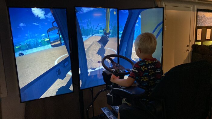 Pojke använder lastbilssimulator med flera skärmar hemma, körspel, virtuell verklighet.