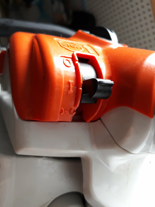 Närbild av en orange och vit elektrisk enhet med en stoppknapp.