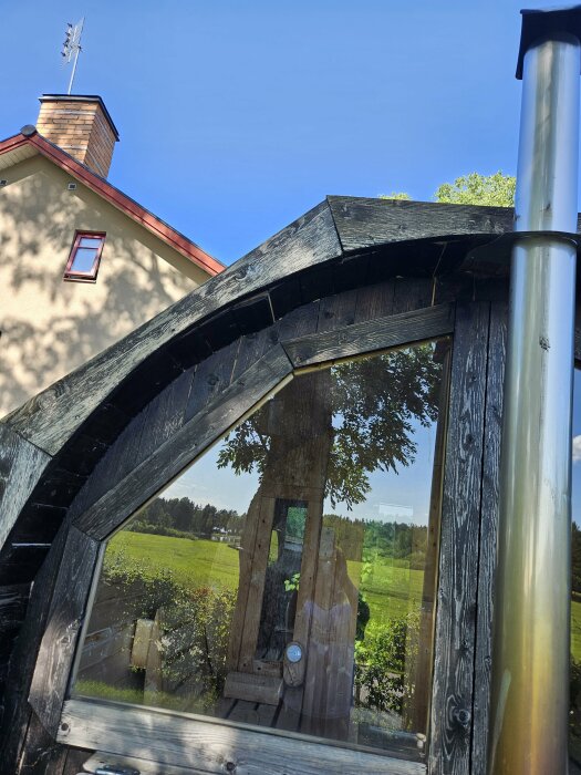 Trävindkvarn spegelreflektion, hus,klädstreck, träd, klar himmel.