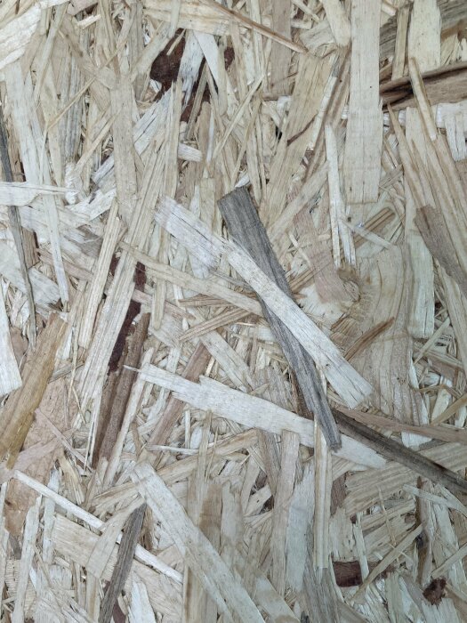 En närbild av OSB-skiva (oriented strand board), byggnadsmaterial bestående av ihoppressade träflisor.