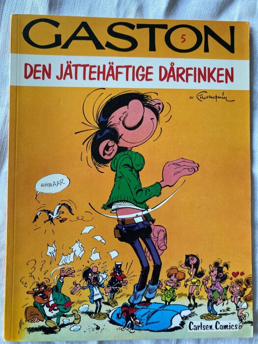 En tecknad seriebok med titeln "Gaston - Den jättehäftige dårpunken", omslag visar karaktärer i olika komiska situationer.