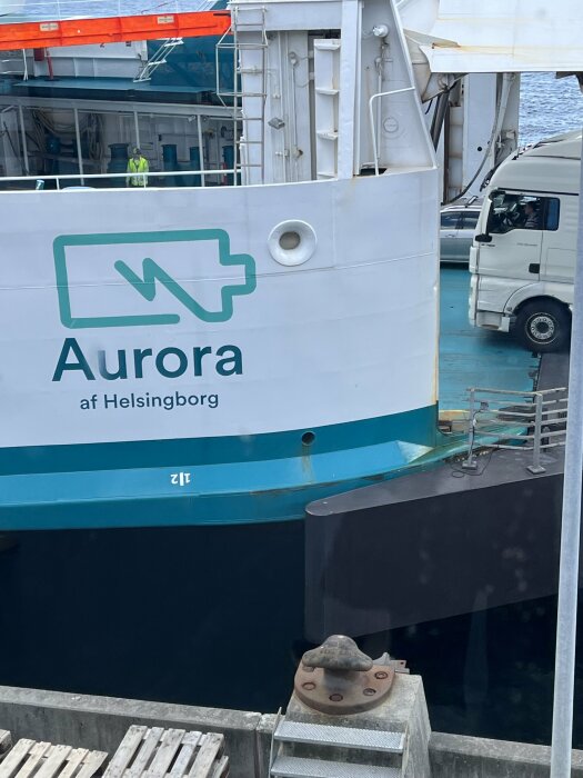 Fartyg med namnet "Aurora af Helsingborg", lastbil, brygga, delvis synlig person på fartyget.