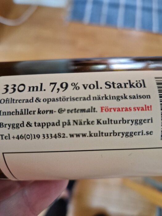 Etikett på ölflaska. Starköl 7,9 % vol. Ofiltrerad, opastöriserad. Närke Kulturbryggeri kontaktinformation.