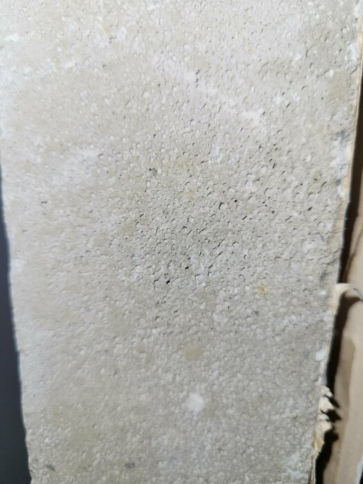 Närbild på en grov, porös betongvägg med synlig grus och sandstruktur.