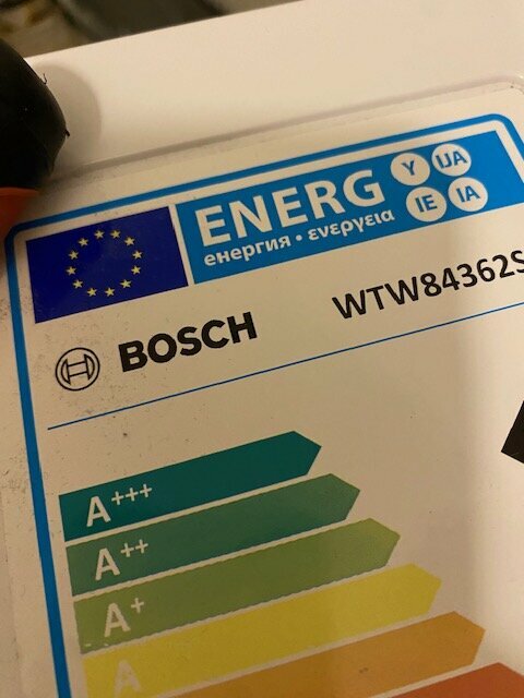 Energimärkningsklistermärke, BOSCH, EU-flagga, energiklass A+++, grönt till gult färgschema, modellnummer, delvis täckt av hand.