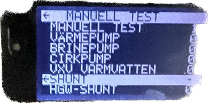 Digital display med text: "MANUELL TEST VÄRMEPUMP BRINEPUMP CIRKPUMP UXV VARMVATTEN SHUNT AGG-SHUNT". Inställningsmeny, teknisk utrustning.