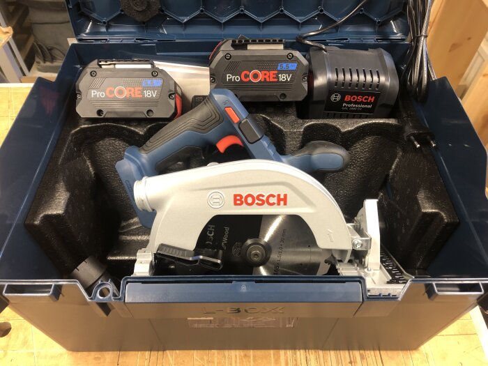 Bosch cirkelsåg med batterier och laddare i förvaringslåda. Verktyg för snickeri, byggjobb.